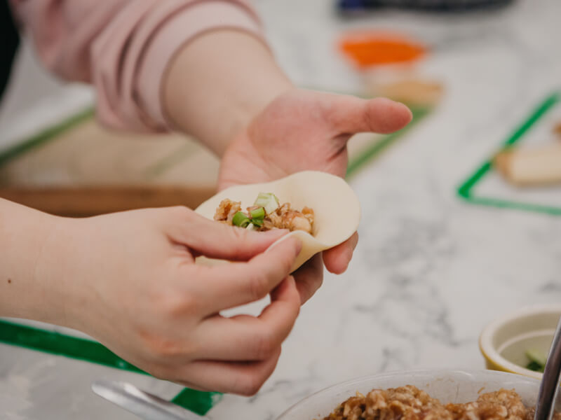 A hand holding an open handmade dumpling.